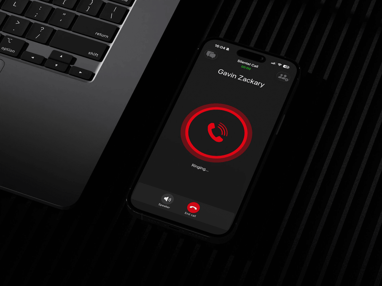 A phone showing an active Silentel call, resting on a desk beside a laptop keyboard.
